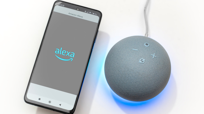 Smartphone with Alexa icon on screen next to an Amazon Echo device