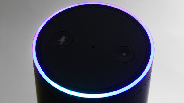 Woman standing next to Alexa device holding a cup of coffee