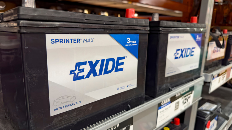 Exide car batteries sitting on a shelf at a store.