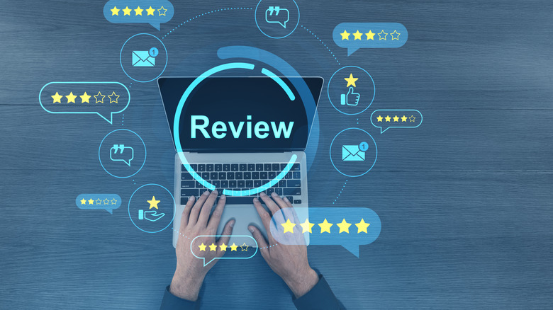 Hands typing on laptop with hovering reviews infographics