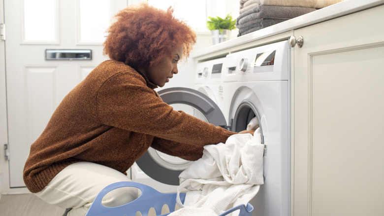 Young woman loading clothes into a washing machine