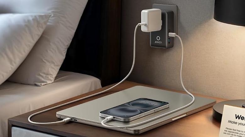 a hotel room with a selection of devices charging on the bedside table