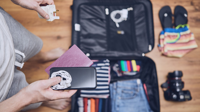 Man preparing for a trip by packing their travel bag with gagdets