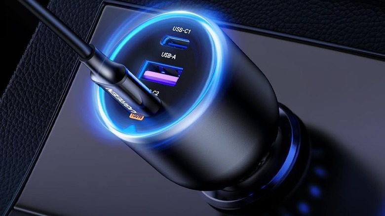 The Ugreen 130W USB-C car charger plugged into a car's power outlet and glowing blue.