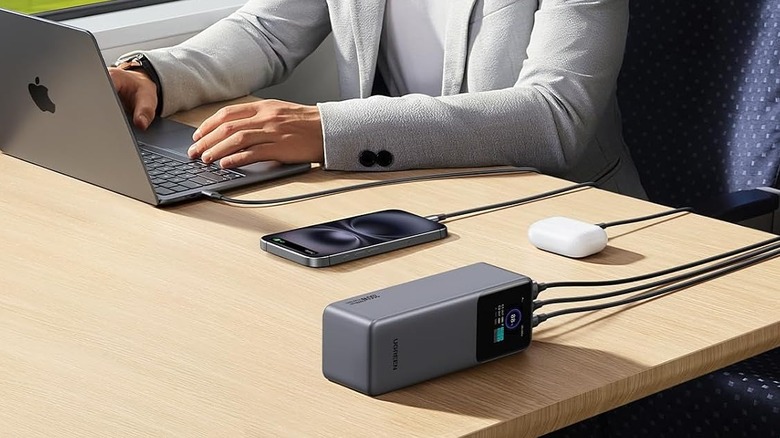 A Ugreen power bank charging a laptop, a phone, and wireless earbuds at the same time.