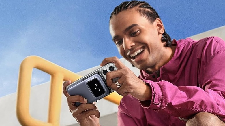A person smiling at their phone being charged by the Ugreen Uno 10,000mAh wireless power bank.