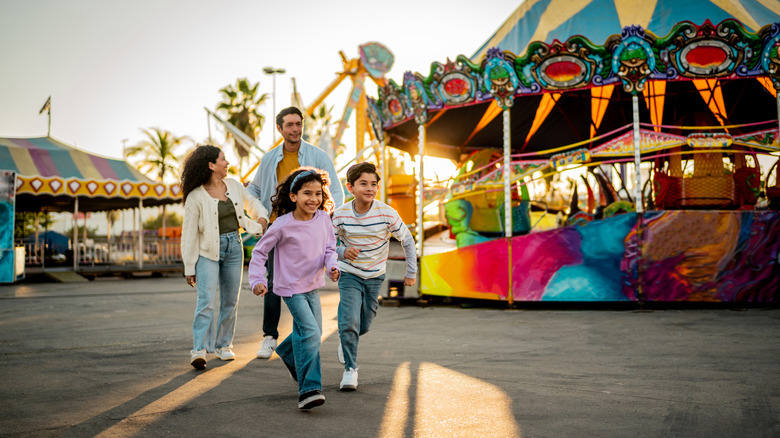 A family in an amusement park, with the kids running.