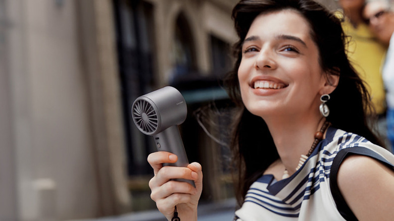 A woman using the JisuLife Pro1S handheld fan outdoors.