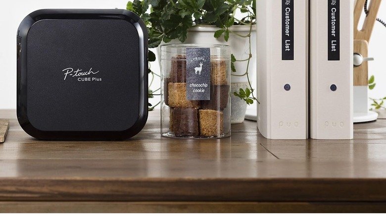 Cube plus label printer on a desk with chocolate and customer list label samples next to it