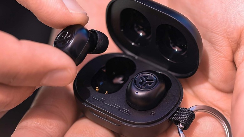 A hand placing JLab JBuds Mini wireless earbuds in their case.