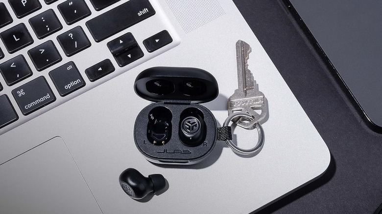 The JLab JBuds Mini wireless earbuds as a keychain resting on top of a MacBook.
