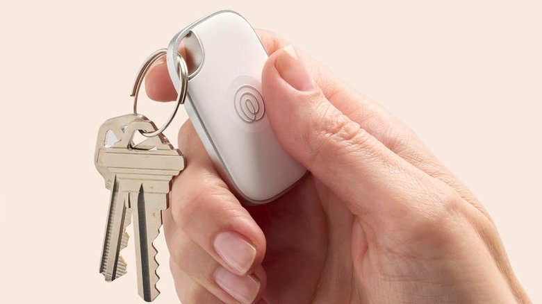 A person holding the Life360 Tile Pro Bluetooth tracker, used as a keychain.
