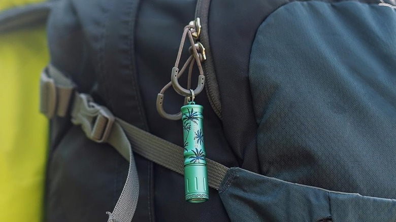 The Olight i3E EOS flashlight attached to the zipper of a backpack.