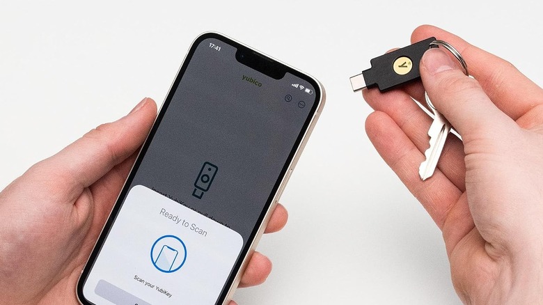 A person inserting the Yubico YubiKey 5C NFC security key into a smartphone.
