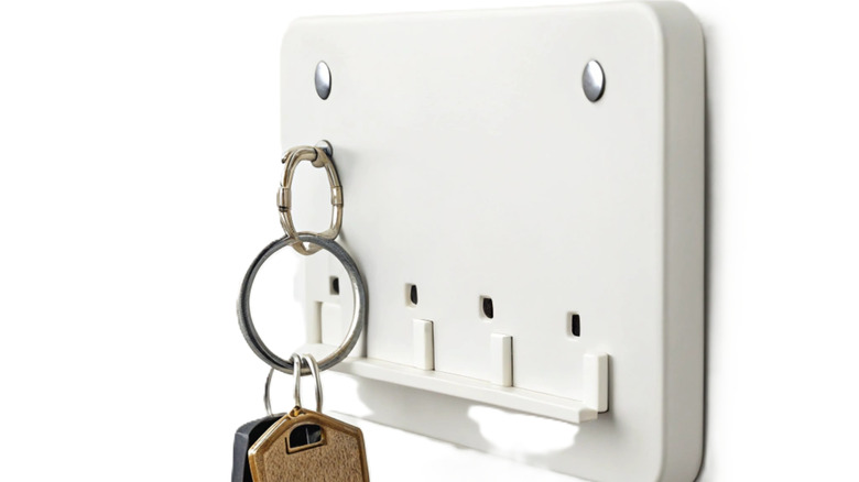 A white plastic key organizer mounted to a white wall.