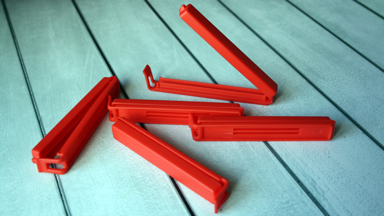 Red plastic bag clips on a wooden background.