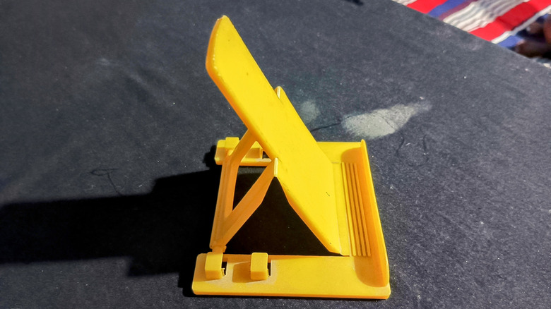 A phone dock made from yellow plastic.