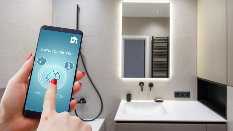 a person using their smartphone to view a water leak sensor alert