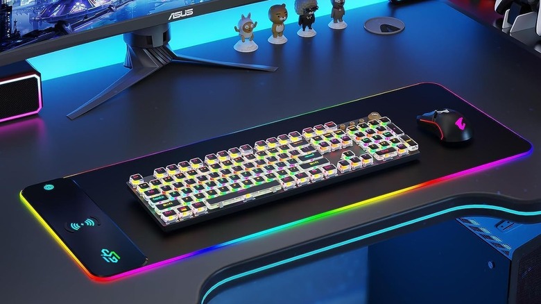 The GIM Wireless Charging RGB Mouse Pad on a desk with a keyboard and mouse on top of it, in front of a computer monitor.