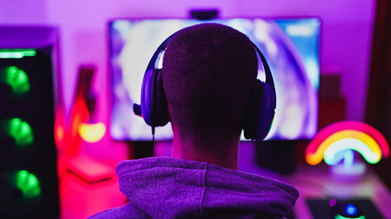 A man wearing a gaming headset while playing video games on a computer monitor.