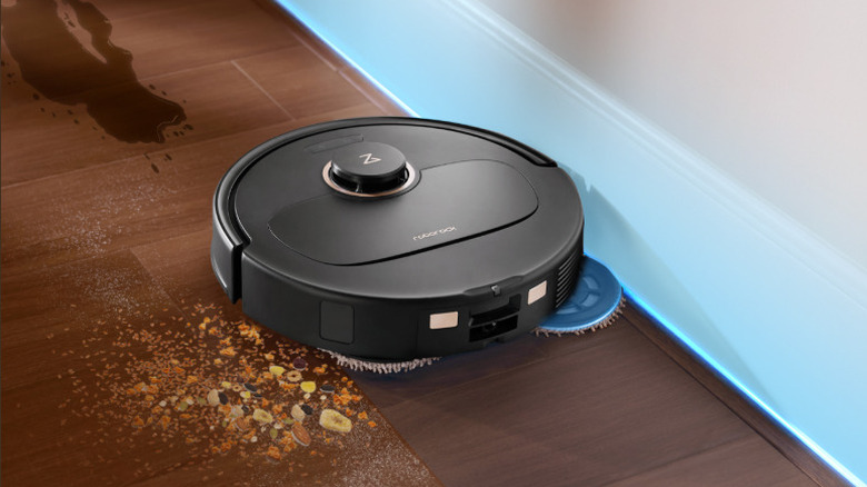 The Roborock Qrevo S5V robot vacuum and mop cleaning a spill on a wooden floor.
