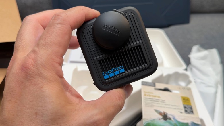 Hand holding up the GoPro Max2 camera with packaging in the background