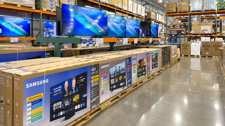 Rows of TVs on display on shelf above boxed TVs in aisle at Costco