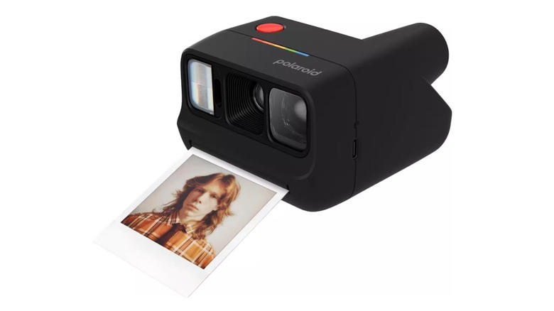 The Polaroid Go Gen 3 instant camera printing a photo on a white background.