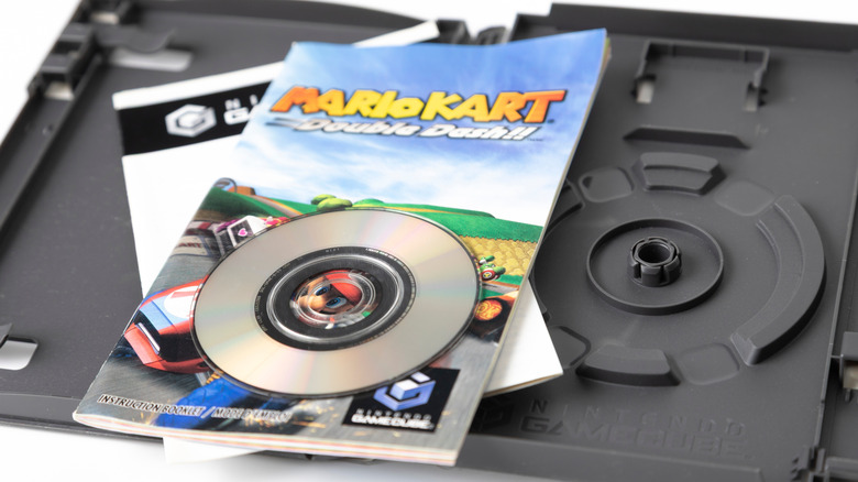A Mario Kart Double Dash GameCube game disk placed atop the manual and an open game case.