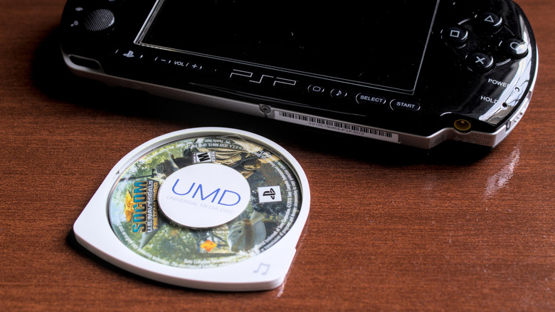 A Universal Media Disc of "SOCOM U.S. Navy SEALs: Fireteam Bravo" placed beside a black PSP on a wooden surface.