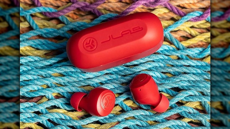 Red JLab Go earbuds on a knitted fabric.