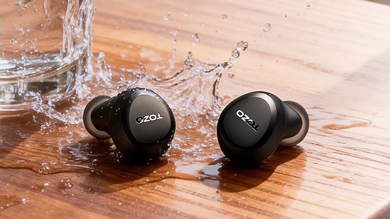Earbuds placed on a wet, wooden surface.