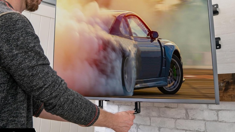 A man pulls an above-fireplace TV mount down by its handles.
