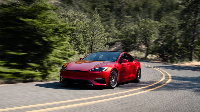 The Tesla Model S Plaid driving through a forest road