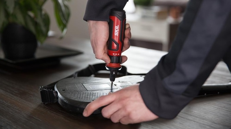 Close up of someone using a Skil rechargeable cordless screwdriver on an electric guitar