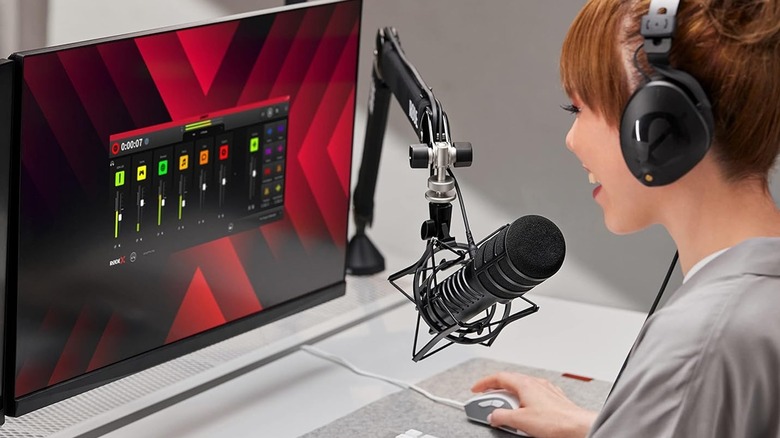 Woman wearing headphones using a Rode microphone with the Rode app open on a laptop.