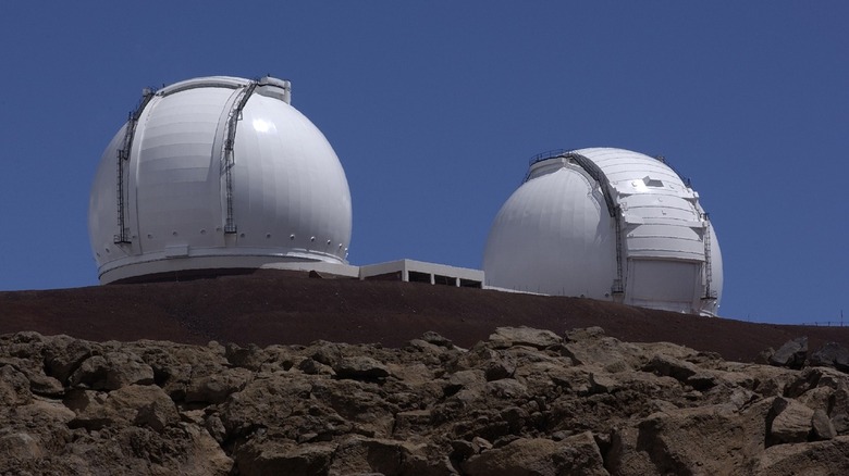 Photo of Keck and Keck II with mountain rocks and a clear blue sky framing the telescopes