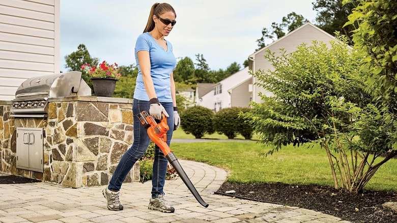 A woman using the Black+Decker LSW40C leaf blower outdoors.