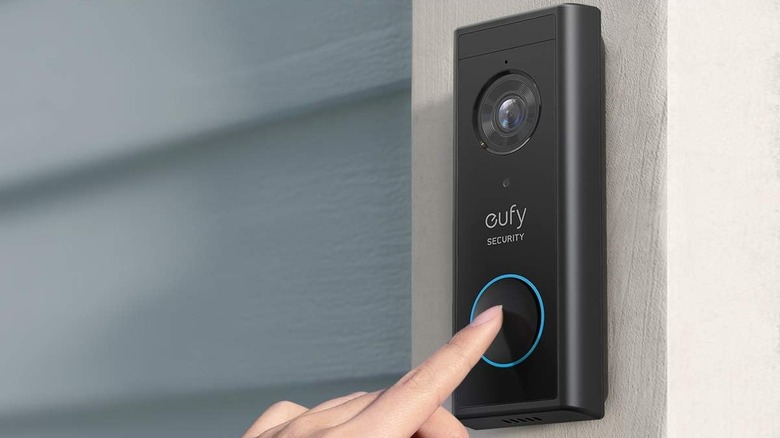 A person pressing the Eufy S220 video doorbell with their finger.