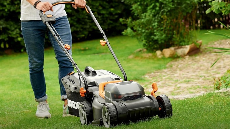 A person using the Worx WG779 lawn mower to cut grass.