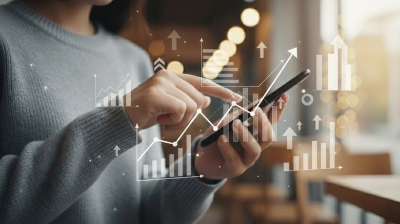 Person pointing at their smartphone with multiple graphs floating around it