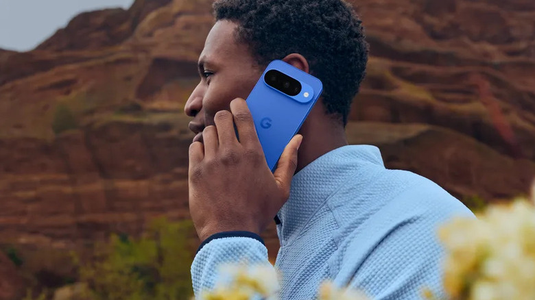 A person taking a call on the Google Pixel 10 Pro with red rock cliff in the background