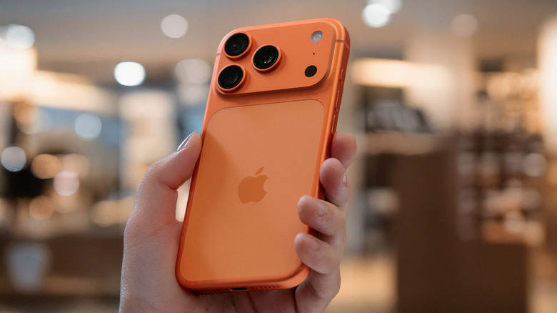 A person holding an orange iPhone 17 Pro Max at a slight angle