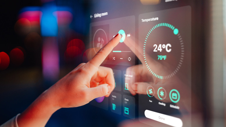 Close up of woman hand controlling smart home devices from a control panel