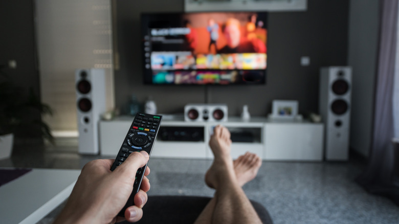 Person browsing through television channels with remote control