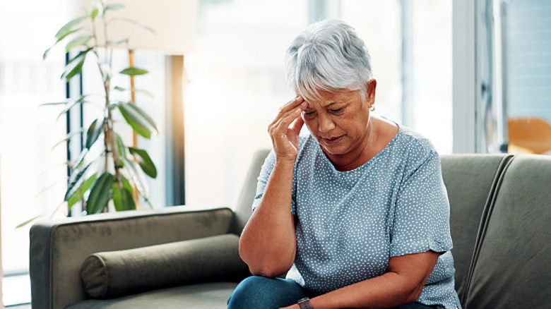 An old person holding their head in distress