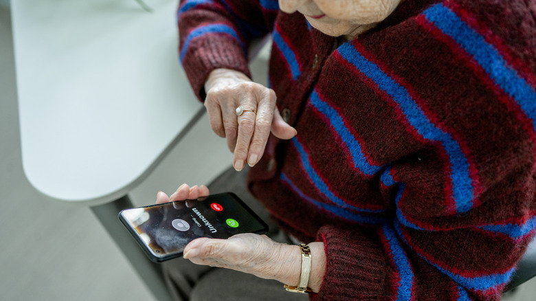 An old person getting a call from an unknown number on their phone
