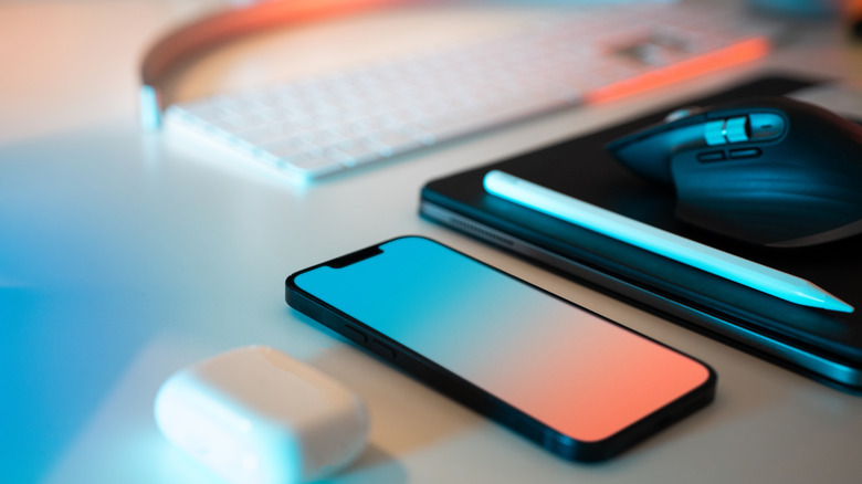 A phone, tablet, stylus, and keyboard on a table
