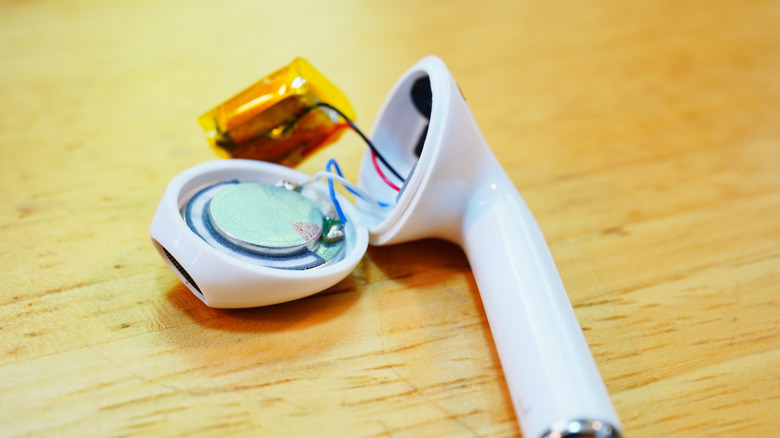 An AirPod broken open with its internals visible.