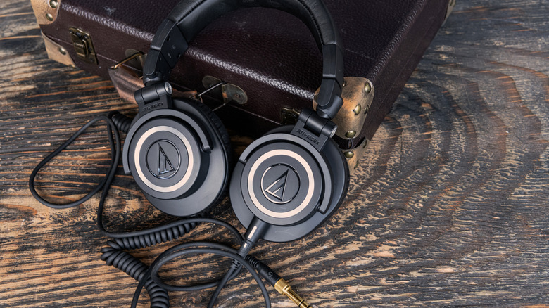 A pair of headphones leaning on a briefcase, with a wire attached.